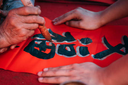 People write Spring Festival couplets with brushes to celebrate Chinese New Year. Chinese traditonal art. Foreign text chinese calligraphy characters means good fortune.の写真素材