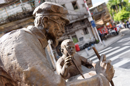 Old man is teaching a boy writing calligraphy for chinese new year. A bronze statue called impression of Spring Festival couplets in kuai zi road, Foshan, Guangdong, China.のeditorial素材