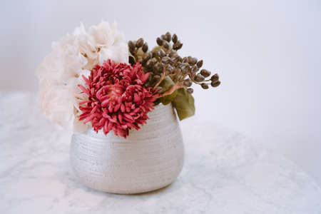 Vase filled with fake flowers on a white marble table. Still life, home Decorations.の写真素材