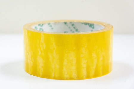 A roll of yellow sealing packing tape isolated on white background. Carton Packing sealing Tool.