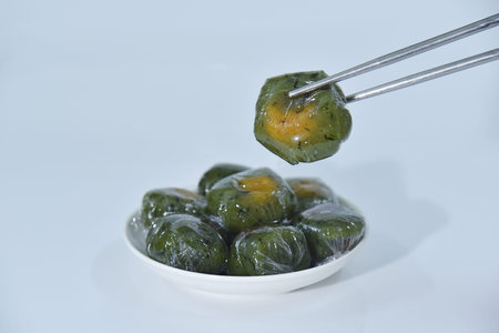Pick up a qingtuan stuffed with egg yolk and dried meat floss with chopsticks. Traditional seasonal Chinese delicacies in Jiangnan area around the time of Tomb Sweeping Day.の写真素材