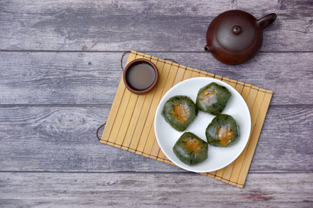 A plate of Qingtuan stuffed with egg yolk and dried meat floss and tea on table. Traditional...