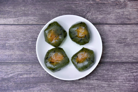 A plate of Qingtuan stuffed with egg yolk and dried meat floss on wooden table. Traditional seasonal...