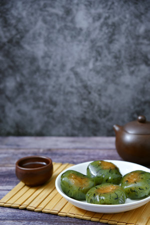 A plate of Qingtuan stuffed with egg yolk and dried meat floss and tea on table. Traditional seasonal Chinese delicacies around the time of Tomb Sweeping Day.の写真素材
