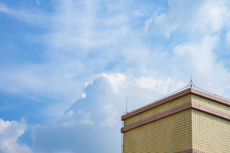A corner of a building under a blue sky. Blue sky with clouds. Fine weather.