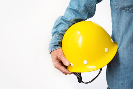 A construction worker holds a yellow hard hat in his right hand. Portrait of a Chinese male engineer...