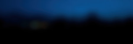 Nighttime landscape with deep blue sky and silhouettes of distant hills in a serene natural settingの素材