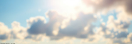 Bright sunlight filters through fluffy clouds on a clear day over a serene landscapeの素材