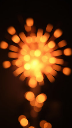 Bright orange fireworks burst against a dark sky, celebrating an event with vibrant lights and colorsの素材