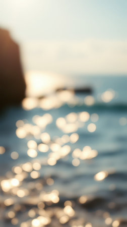 Sunlight sparkles on ocean waves with blurry rocks in the background during a tranquil afternoonの素材