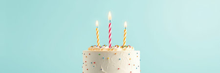 Celebration with a colorful birthday cake topped with candles on a light blue backgroundの素材