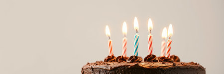 Birthday celebration featuring a chocolate cake with lit candles in a festive settingの素材