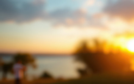 Golden sunset over a serene lake with silhouettes of trees and people enjoying an evening strollの素材
