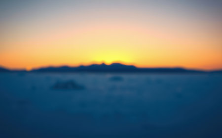 Serene twilight over distant mountains as the sun sets on a tranquil landscapeの素材