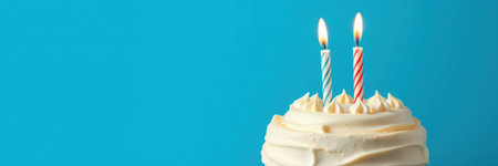 Celebrate a birthday with a decorated cake featuring two colorful candles on a vibrant blue backgroundの素材