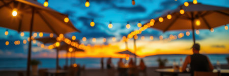 Vibrant sunset casting golden lights over beachside tables with umbrellas during a warm eveningの素材