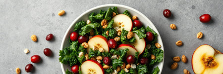 Fresh green salad with apple slices, cranberries, and nuts on a gray backgroundの素材