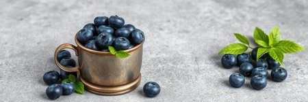 Fresh blueberries in a vintage cup with leaves on a textured surfaceの素材