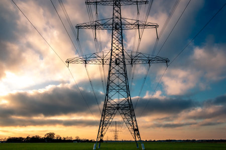 High voltage pylons in a beautiful landscape with colorful clouds in wintertime, tasks in the...