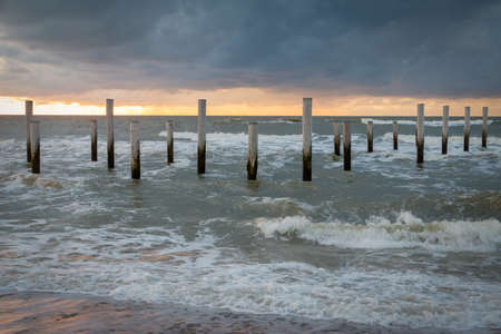 Sunset on the North Sea near the town of Petten, with dark colored clouds and an orange setting sunの写真素材