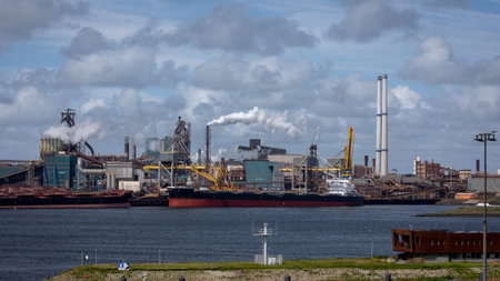 Industrial complex with smoking chimneys in the port of IJmuiden, with transfer points and transport...
