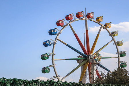Colorful ferris wheel of the amusement park in the blue sky background.