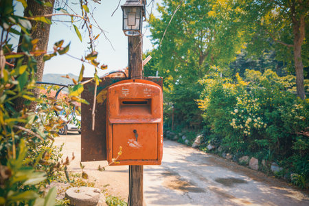Vintage orange mailbox on rural road surrounded by green nature creating peaceful countryside atmosphere