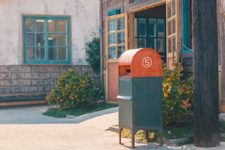 Vintage red mailbox in front of house with plants and warm sunlight creating cozy lifestyle atmosphere