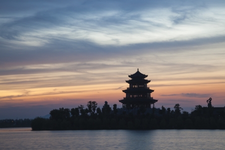 sunset in a lake with chinese ancient tower building の写真素材