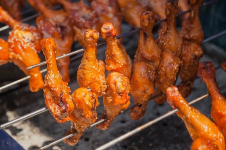 barbecue chicken thighs with sesame seeds and red chili peppers on the grillの写真素材