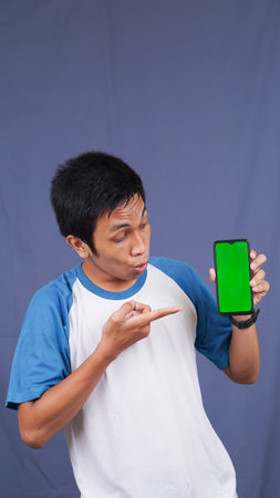 asian man pointing at the green screen handphoneの写真素材