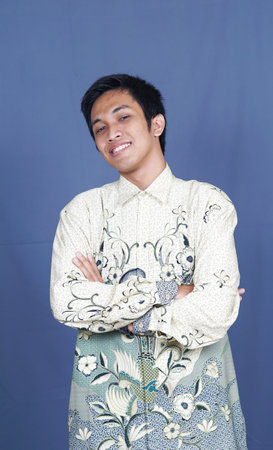 asian man stylish with batik clothes in studio isolated with blue backgroundの写真素材
