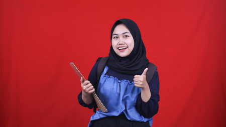 Asian woman wearing hijab student concept happy expression and OK gesture isolated red backgroundの写真素材