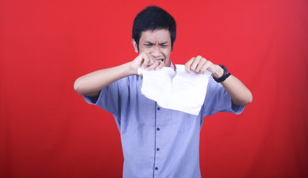 Asian man stress tear the paper isolated red background
