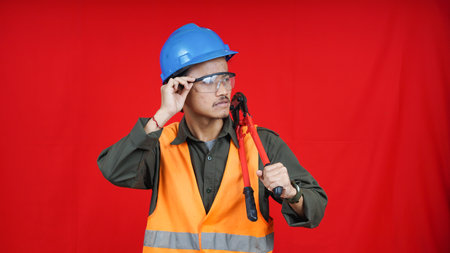 asian construction worker man wearing uniform, helmet, with cutter isolated red backgroubdの写真素材