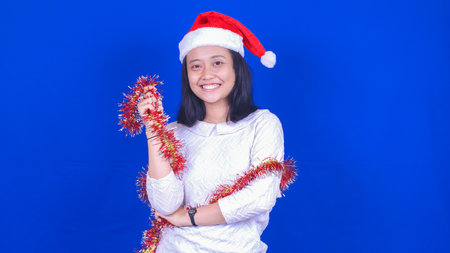 asian woman wearing christmas hat isolated blue backgroundの写真素材
