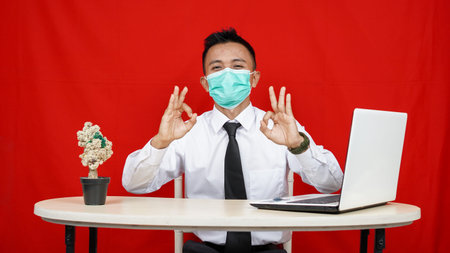 Asian business man wearing mask OK gesture isolated red background