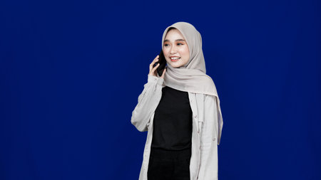 Asian hijab woman calling on the phone isolated blue background