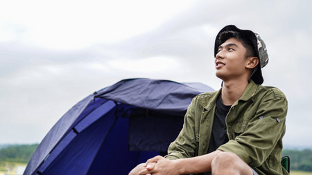 young Asian man enjoy camping at reservoir