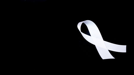 A white awareness ribbon on black background for peace conditionの写真素材