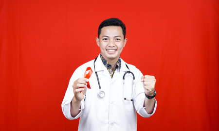 male doctor holding red aids ribbon on hand. National Blood Donor Month in January. World aids day...