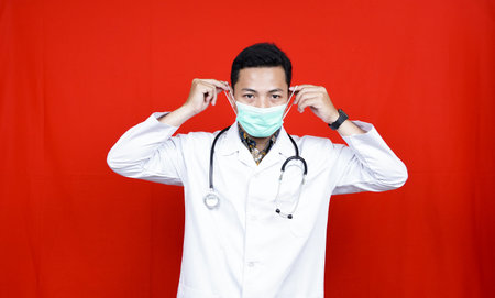Asian Male Doctor wearing mask. Protect from virus isolated red background