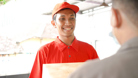 delivery man delivers the box in front of the customer's houseの写真素材