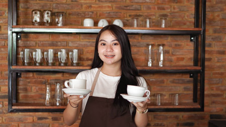 Asian woman barista holding cup for coffeeの写真素材