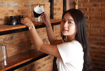 Asian woman barista arranging glasses at cafeの写真素材