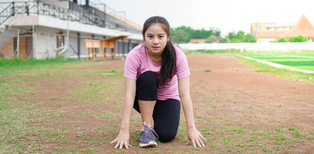 asian woman athlete getting ready to start running on track