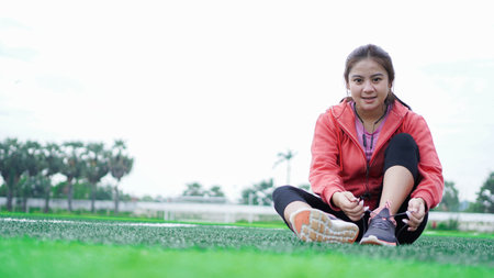 asian woman tying sneakers before runningの写真素材