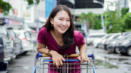 smilling asian woman shopping with trollyの写真素材