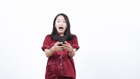 woman wearing pajama shocked see phone isolated white backgroundの写真素材