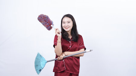 woman wearing pajama hold sulak and broom isolated white backgroundの写真素材
